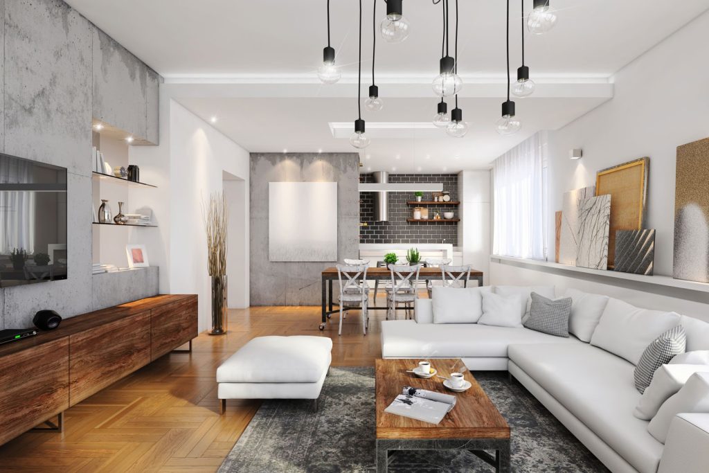 Modern living room with white sectional sofa, wooden furniture, large windows, and hanging lights, leading to an open dining area.