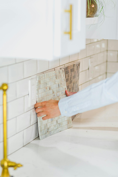 A person renovating a kitchen tile backsplash for a modern look